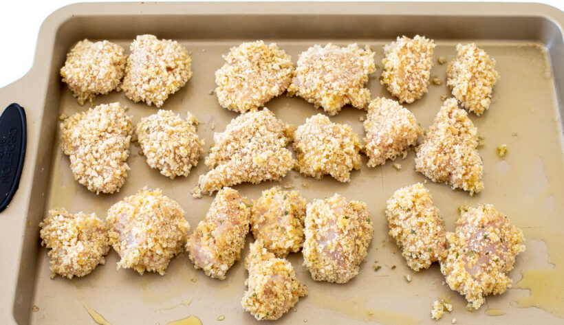 breaded unbaked chicken bites on baking sheet