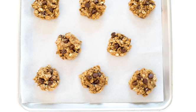 overhead view of several raw cookie dough on a lined baking sheet