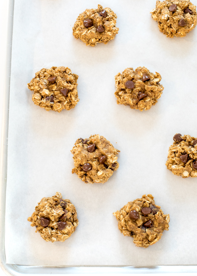 closeup of several raw cookie dough on a lined baking sheet