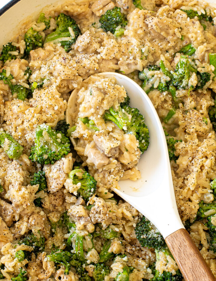 Cheesy chicken broccoli rice skillet with a rubber spoon scooping up a serving. 