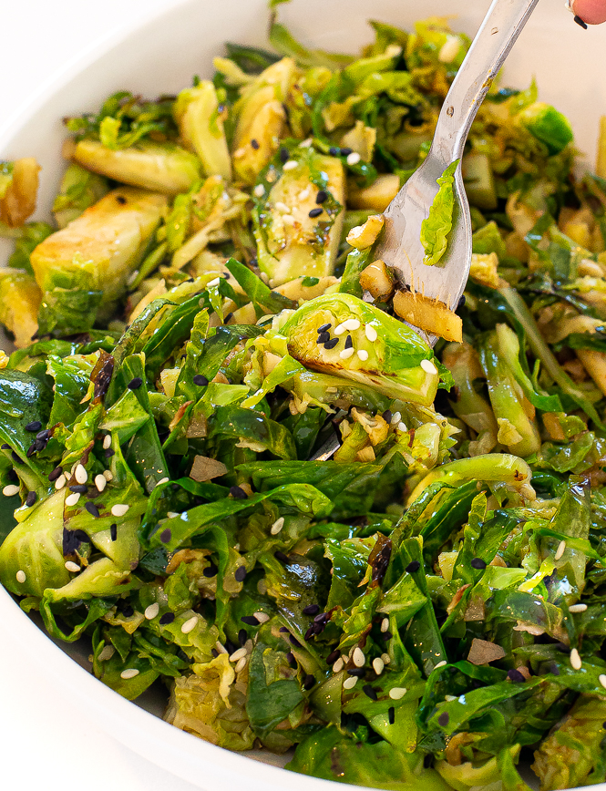 Up close shot of Brussels sprouts in a white bowl with a fork. 