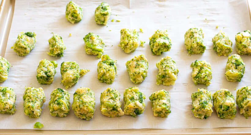 Broccoli cheddar tots on a baking sheet before being baked.