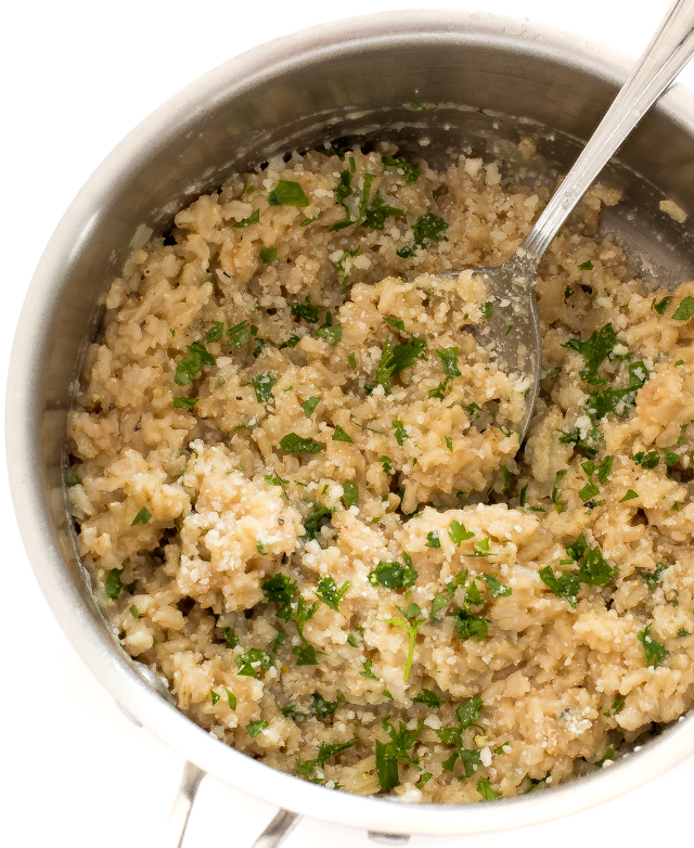 overhead shot of brown rice in saucepan with parsley and parmesan cheese