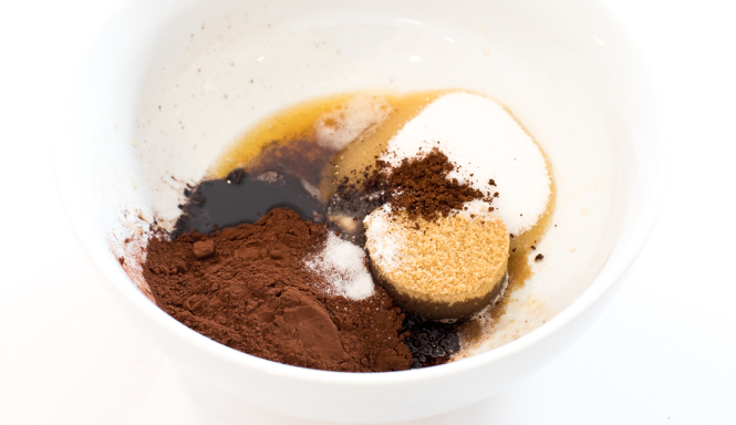 white mixing bowl with cocoa powder, brown sugar, white sugar, melter butter and salt