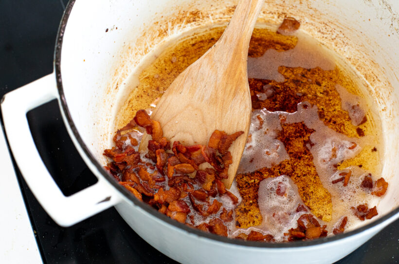 Bacon cooking in the pot on the stove.
