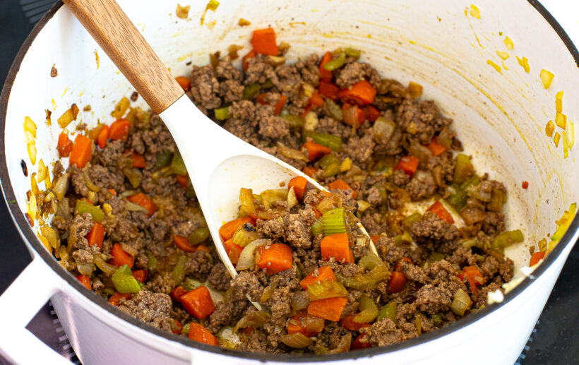 Ground beef being browned with veggies in a pot.