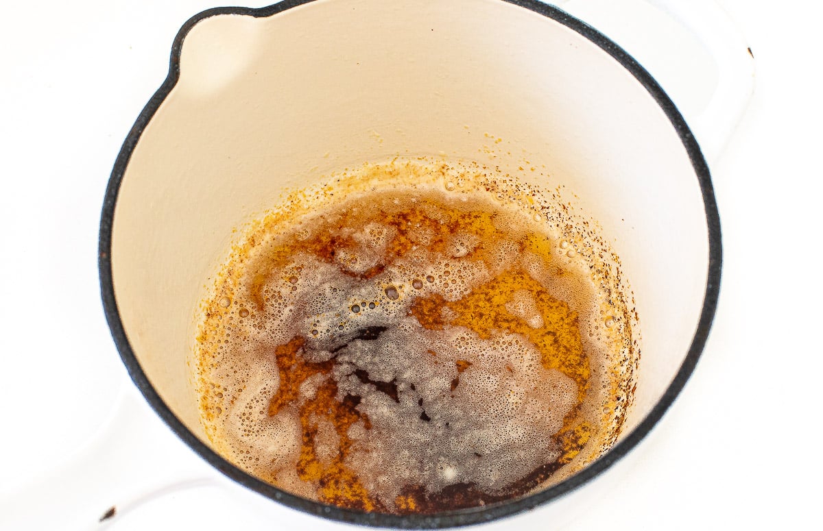 Butter browning in a cream-colored enameled pot.