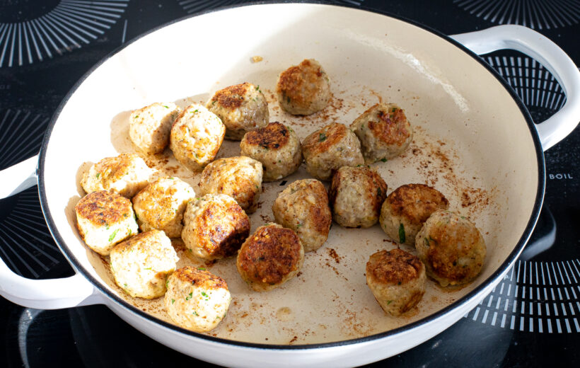 Meatballs in the skillet after being browned on all sides.
