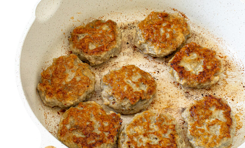 Cooked breakfast sausages in a skillet.
