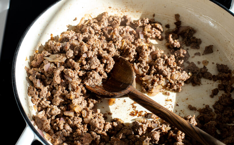 Ground beef and onions cooking in a large skillet. 