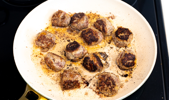 Cooked meatballs in a frying pan.