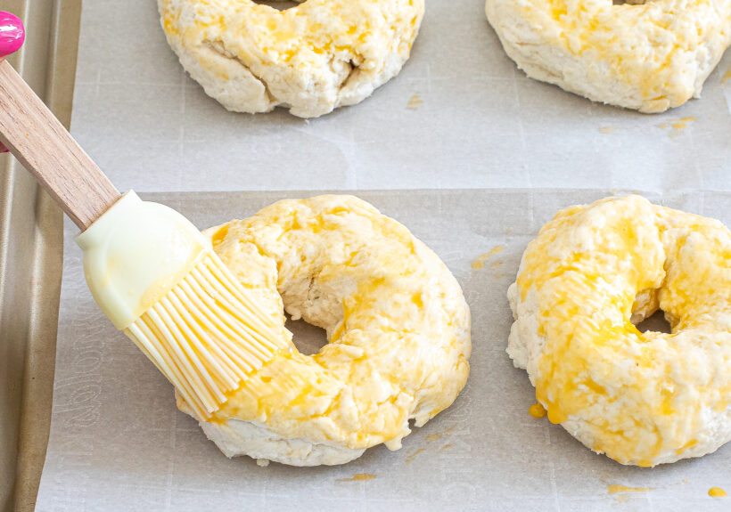Brushing bagels with egg wash.