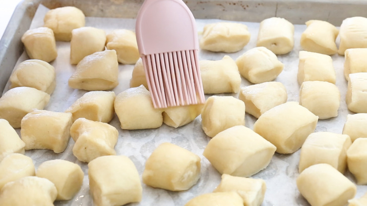 brushing egg wash onto pretzel bites
