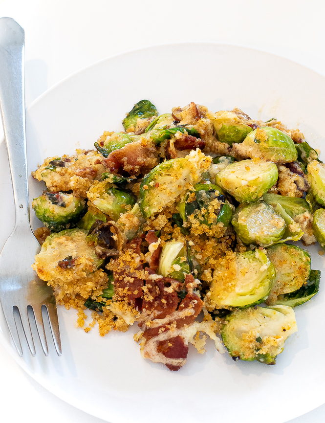 Brussels sprouts served in a white bowl with a silver fork.