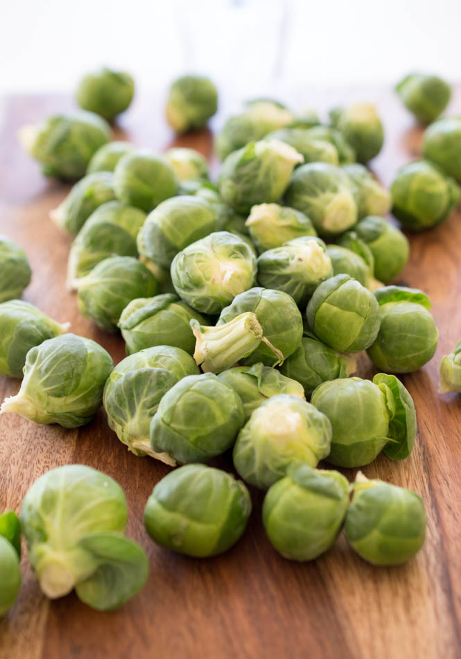 Raw brussels sprouts on a wooden cutting board. 