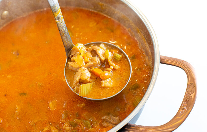 Ladle holding a scoop of buffalo chicken chili.