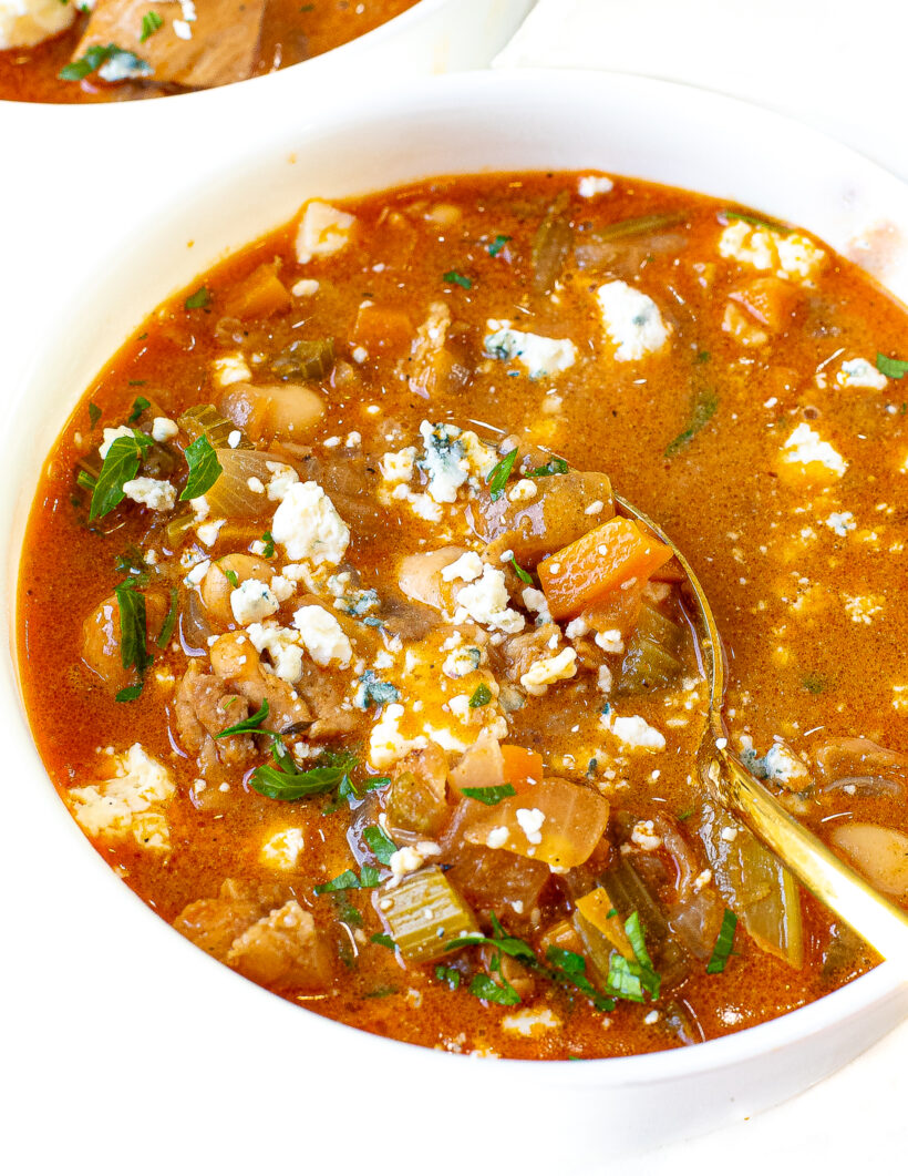 Gold spoon in bowl of buffalo chicken chili.