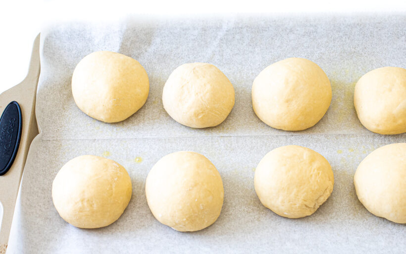 portioned burger buns on baking sheet
