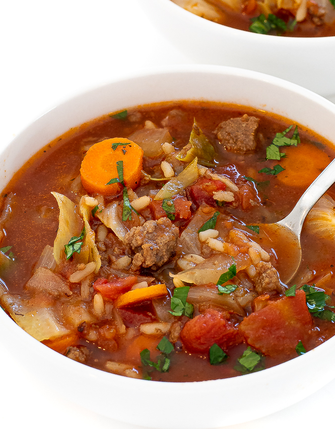 Cabbage soup in a white bowl with a silver spoon.