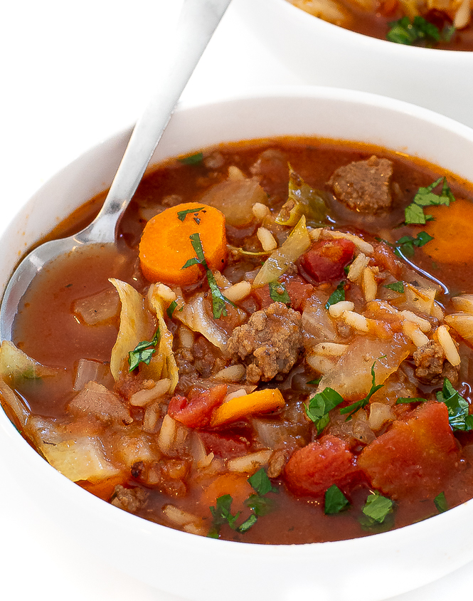 Cabbage roll soup in a white bowl with a silver spoon.