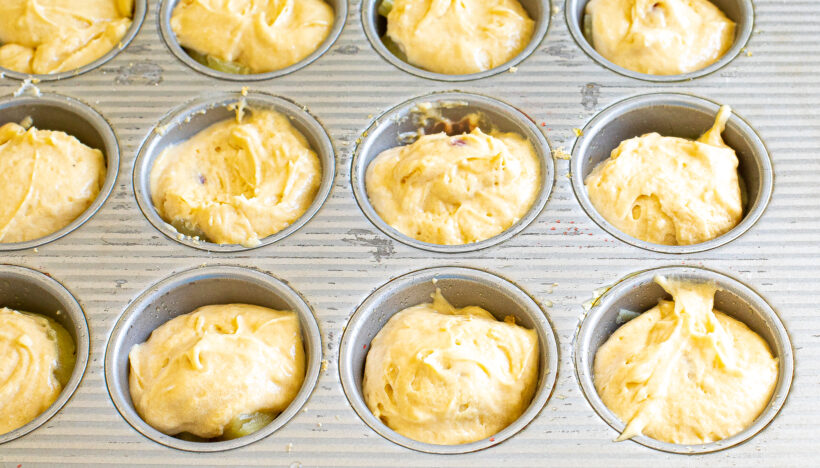 Cake batter added on top of the pineapple rings in the muffin tin.