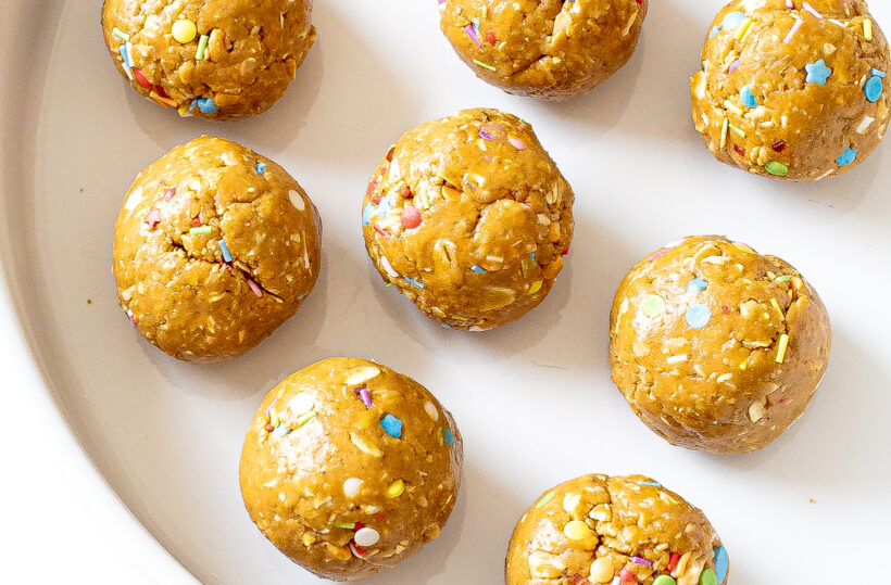 Energy balls rolled into balls and placed on a white plate. 