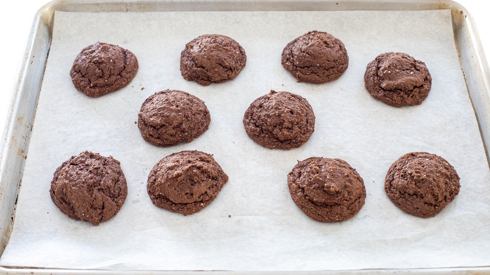baked chocolate cookies cooling on baking sheet lined with parchment paper