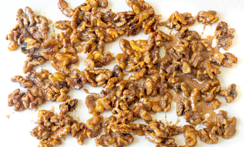 Candied walnuts spread out on a baking sheet.
