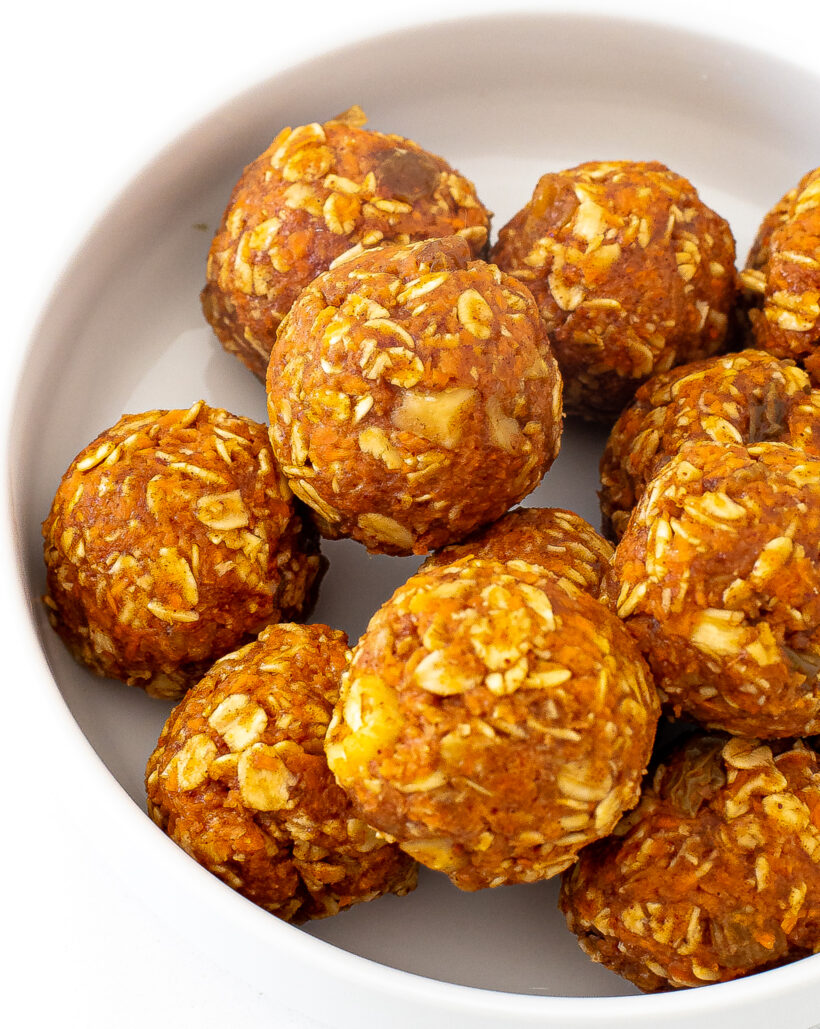Carrot cake energy bites piled together in a white bowl.