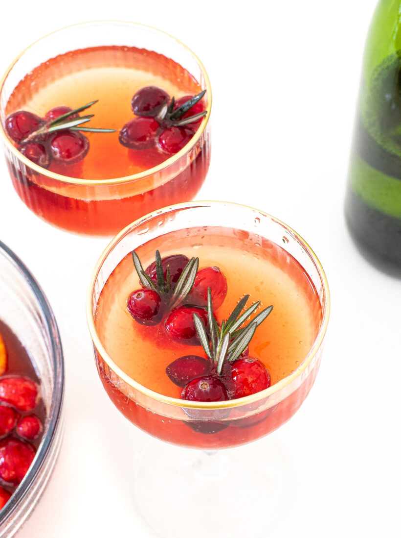 coupe glasses filled with fresh cranberries and rosemary sprigs