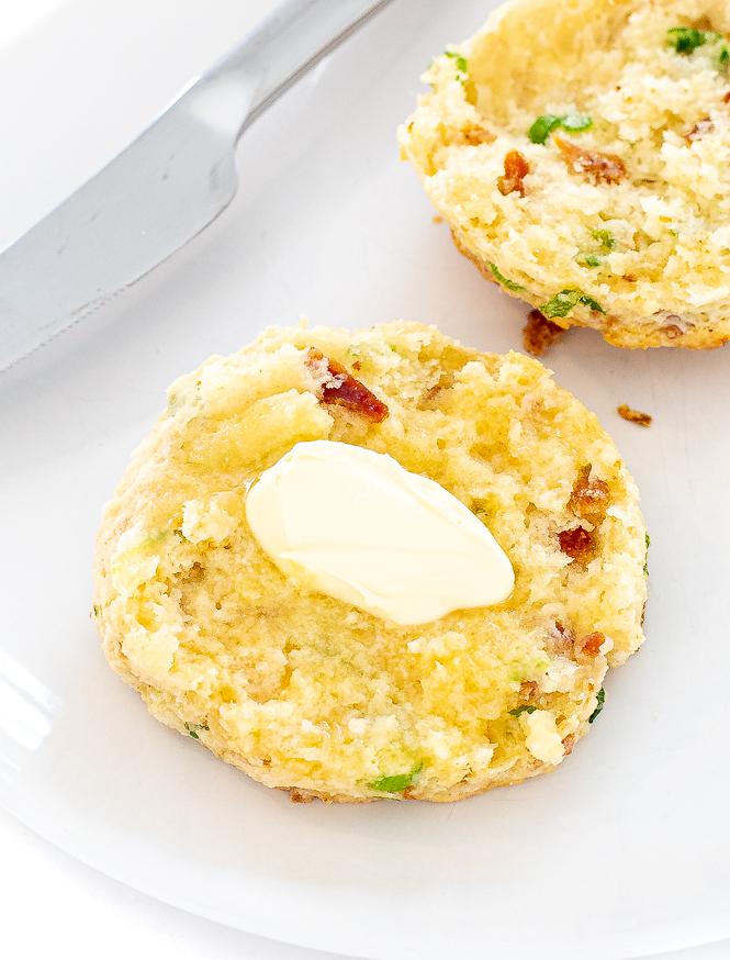 bacon cheddar biscuit cut in half with a slab of melted butter on top