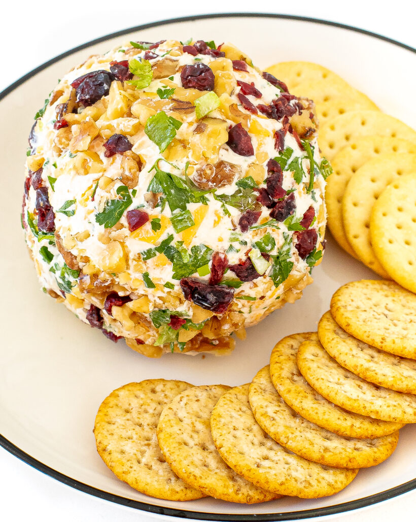A cheeseball on a plate with crackers.
