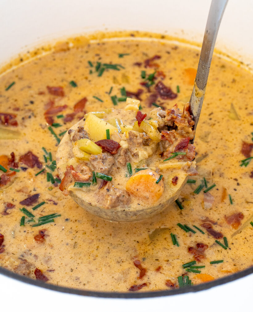 Soup in a large pot with a ladle taking out some soup.