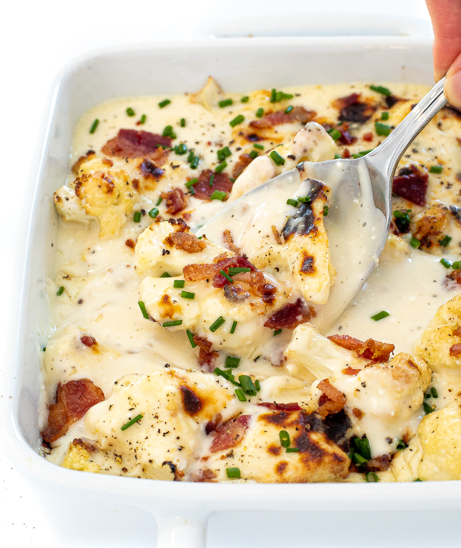 Cauliflower with sauce in a white baking pan with a silver spoon.