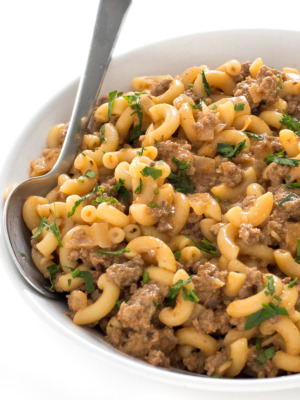 Homemade hamburger helper in white bowl with spoon.