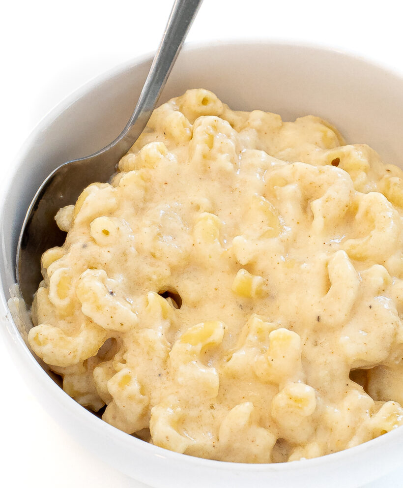 Bowl of creamy three cheese mac and cheese with a spoon.