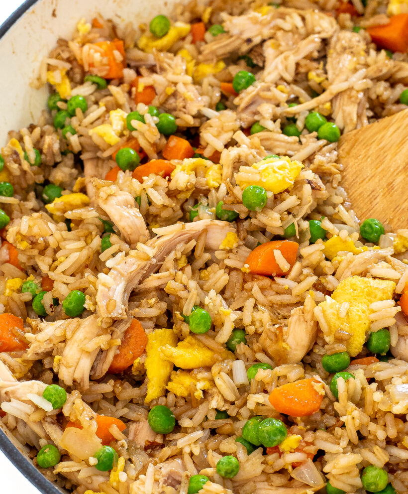 Fried rice with chicken in a pan with a wooden spoon. 