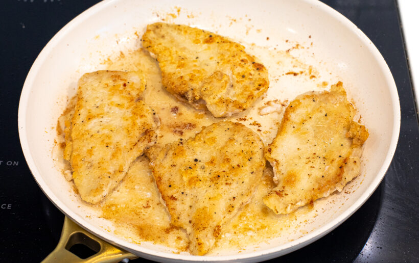 Chicken being sautéed in a skillet.