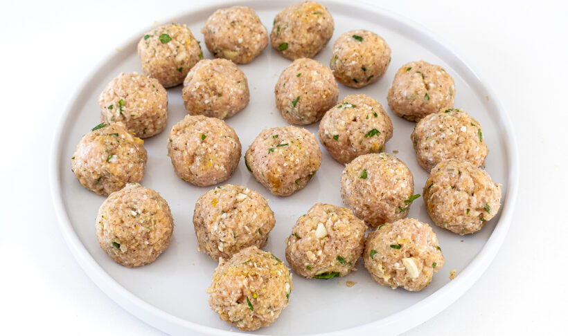 Raw chicken meatballs on a plate.