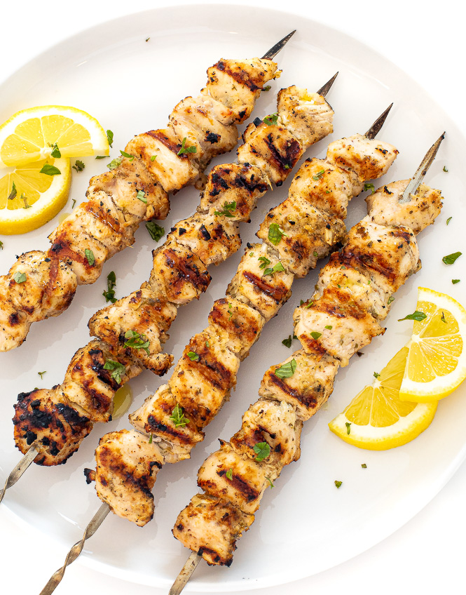 Grilled chicken skewers on a white serving platter.