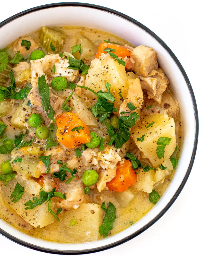 A close up shot of slow cooker chicken stew in a white serving bowl.