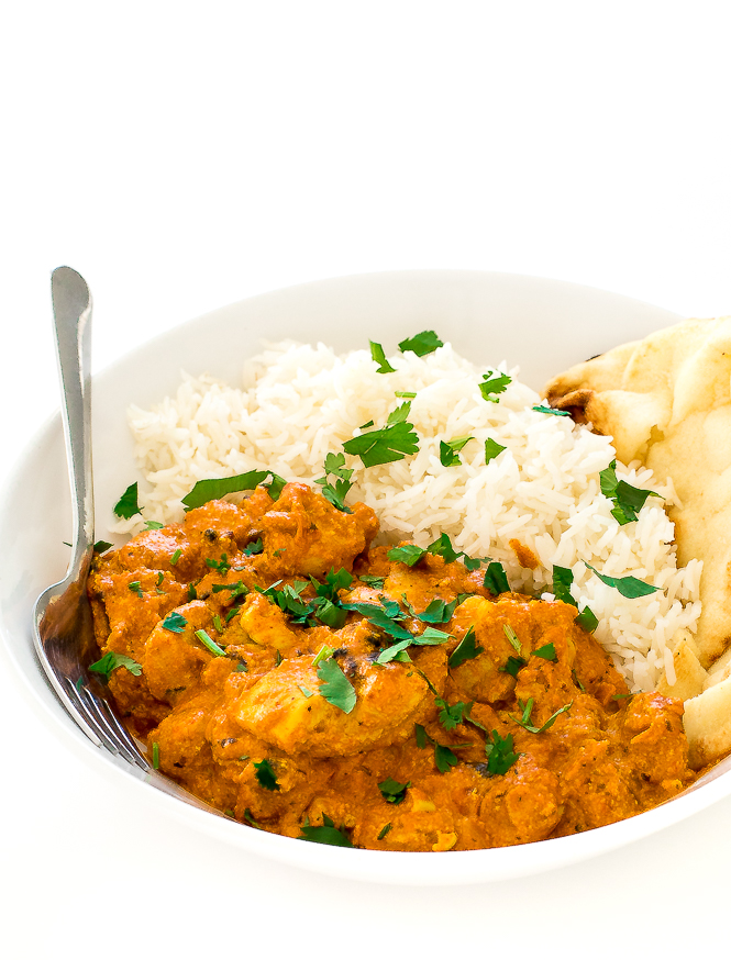Chicken Tikka Masala in a white bowl with white rice, naan, and a fork.