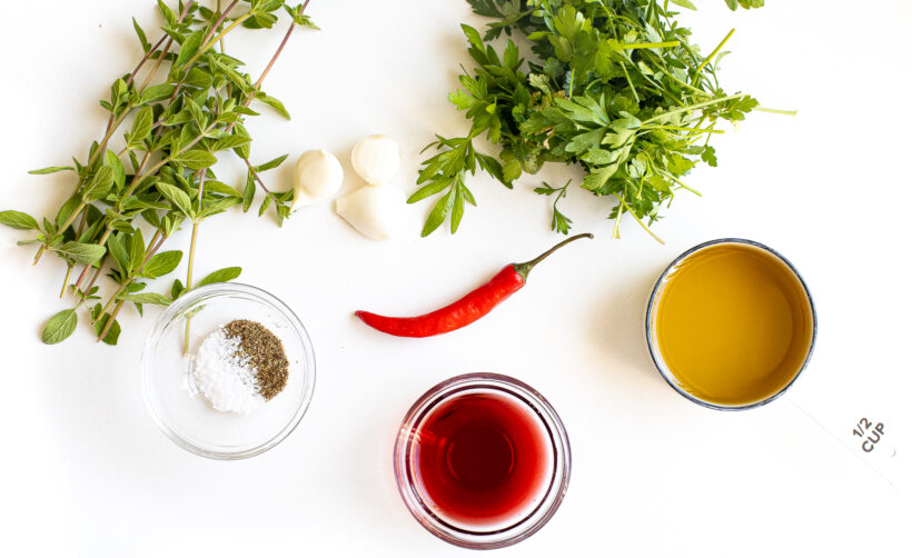 Chimichurri sauce ingredients laid out on a white surface.
