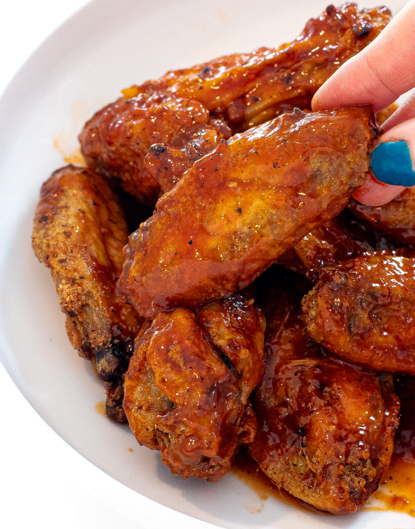 picking up a chicken wing coated in honey chipotle sauce