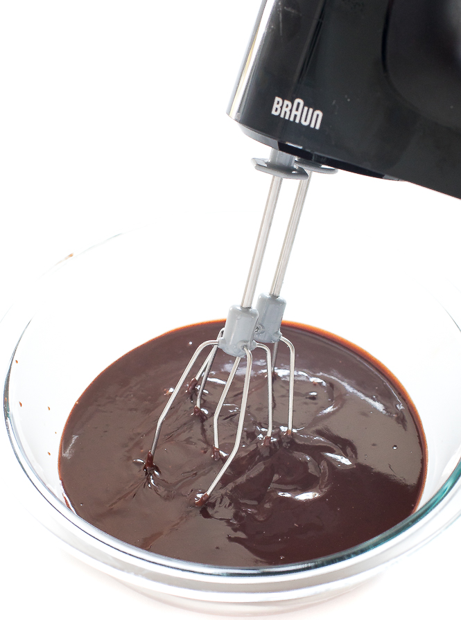 Chocolate Ganache in a clear bowl with a hand mixer