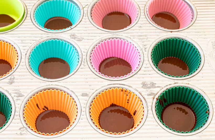 Melted chocolate in the bottom of silicone liners in a muffin tin.