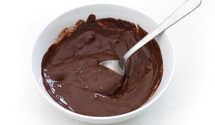 Melted chocolate in a white bowl with a spoon.