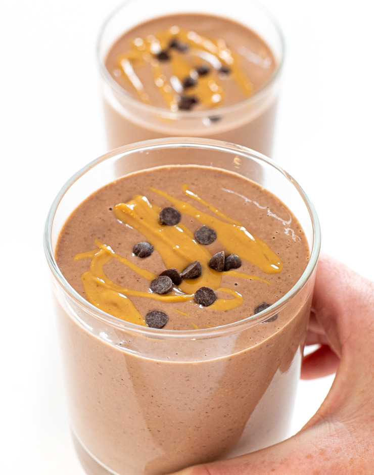 author holding Chocolate Peanut Butter Smoothie topped with peanut butter and mini chocolate chips