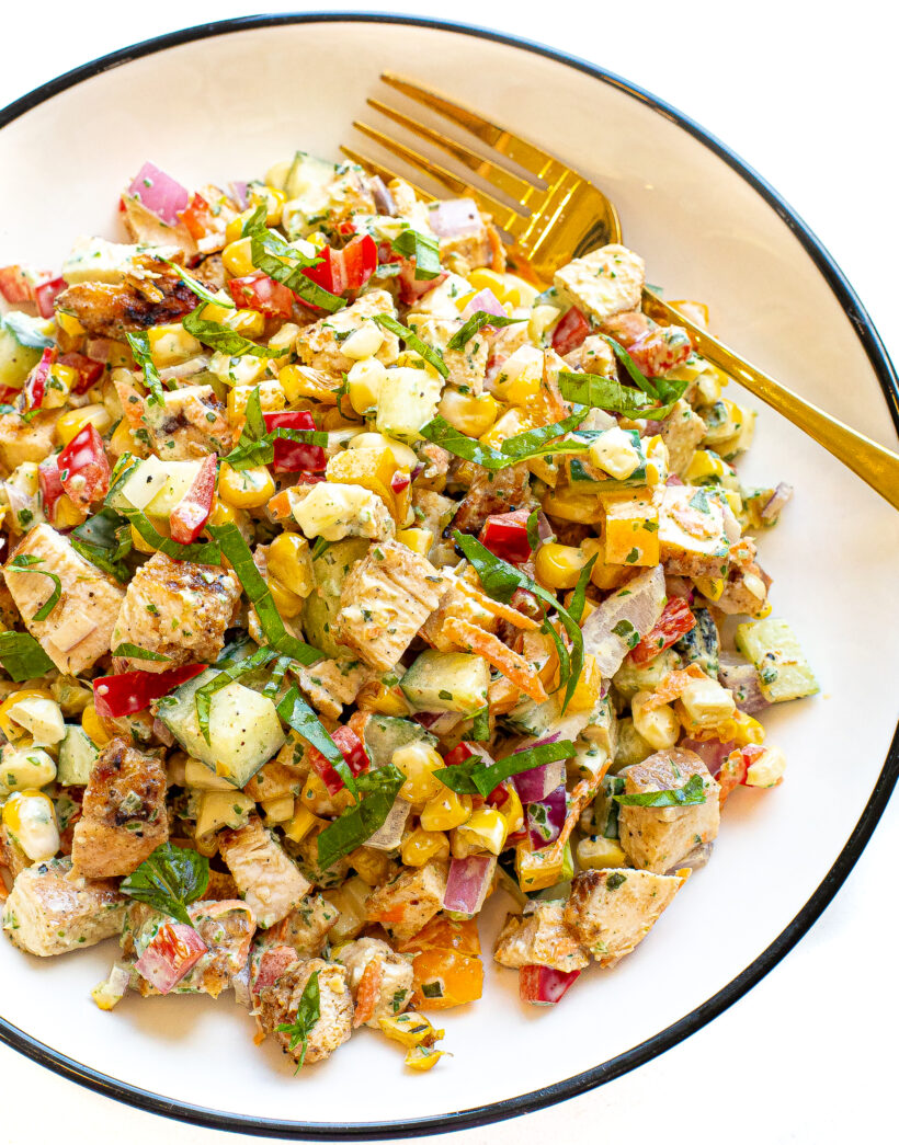 Chopped chicken salad on a white plate with a gold fork.
