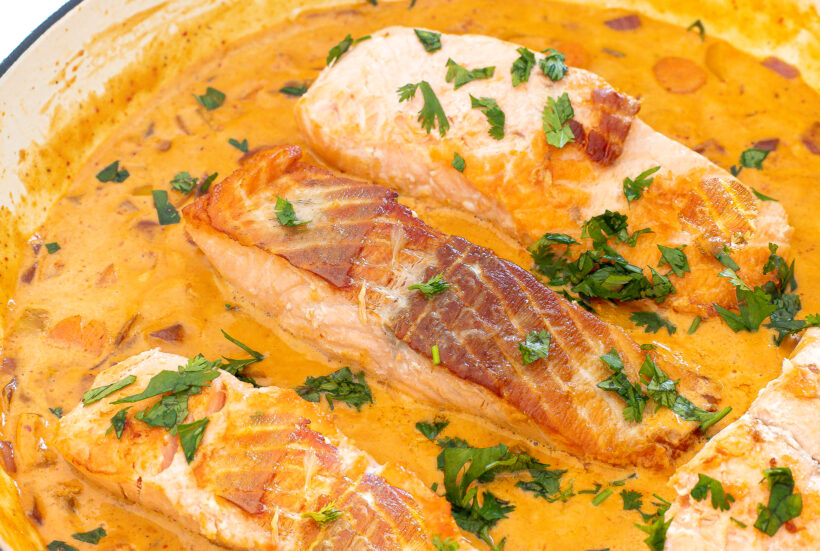 Four salmon filets in a curry sauce.